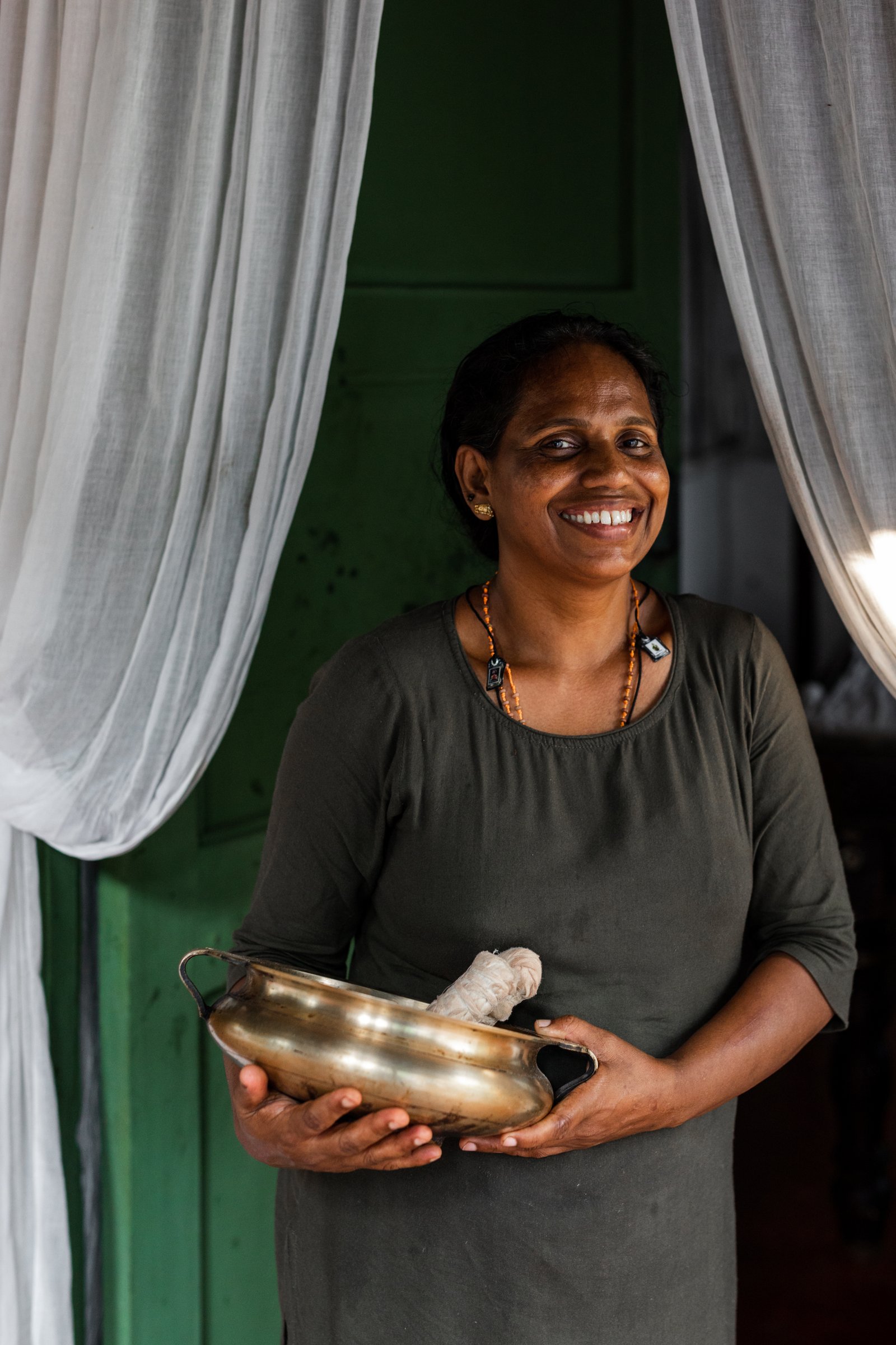A SWAN Ayurveda therapist holding the brass vessel and herbal boluses used in treatment