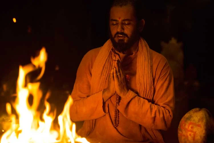 Gyanmitra Saraswati, Co-founder and Yoga teacher at SWAN, seated in prayer before the fire