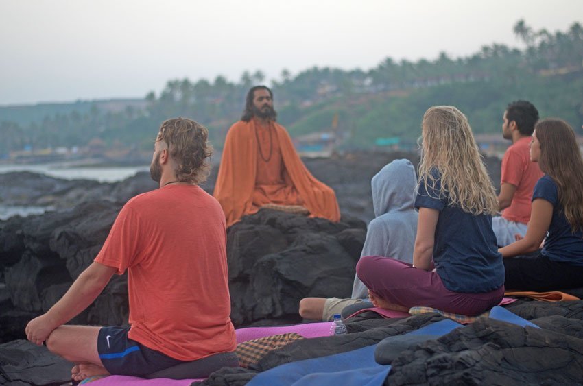 Guests in meditation on the rocks at dusk, guided at SWAN Yoga Retreat